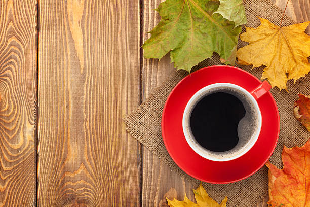 istock Autumn leaves and coffee cup over wood background 517996267