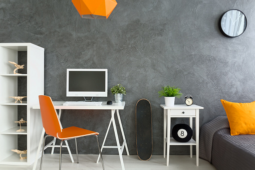 Shot of a grey modern bedroom with orange accessories