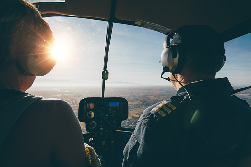 Two pilots in a helicopter while flying on a sunny day. rear view shot of man and woman pilots