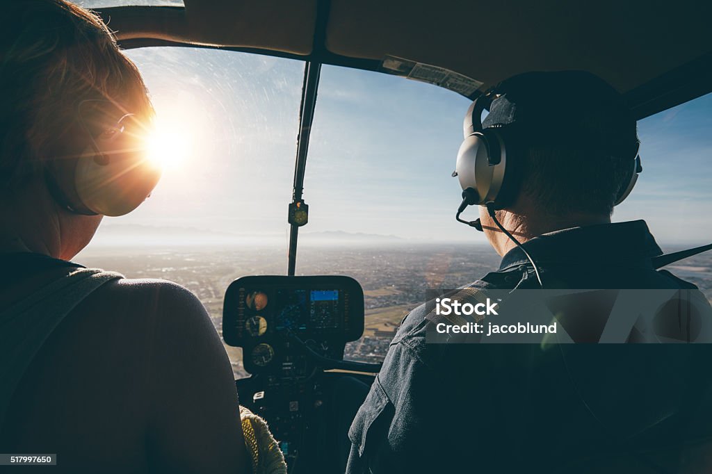 Two pilots in a helicopter flying on a sunny day Two pilots in a helicopter while flying on a sunny day. rear view shot of man and woman pilots Helicopter Stock Photo