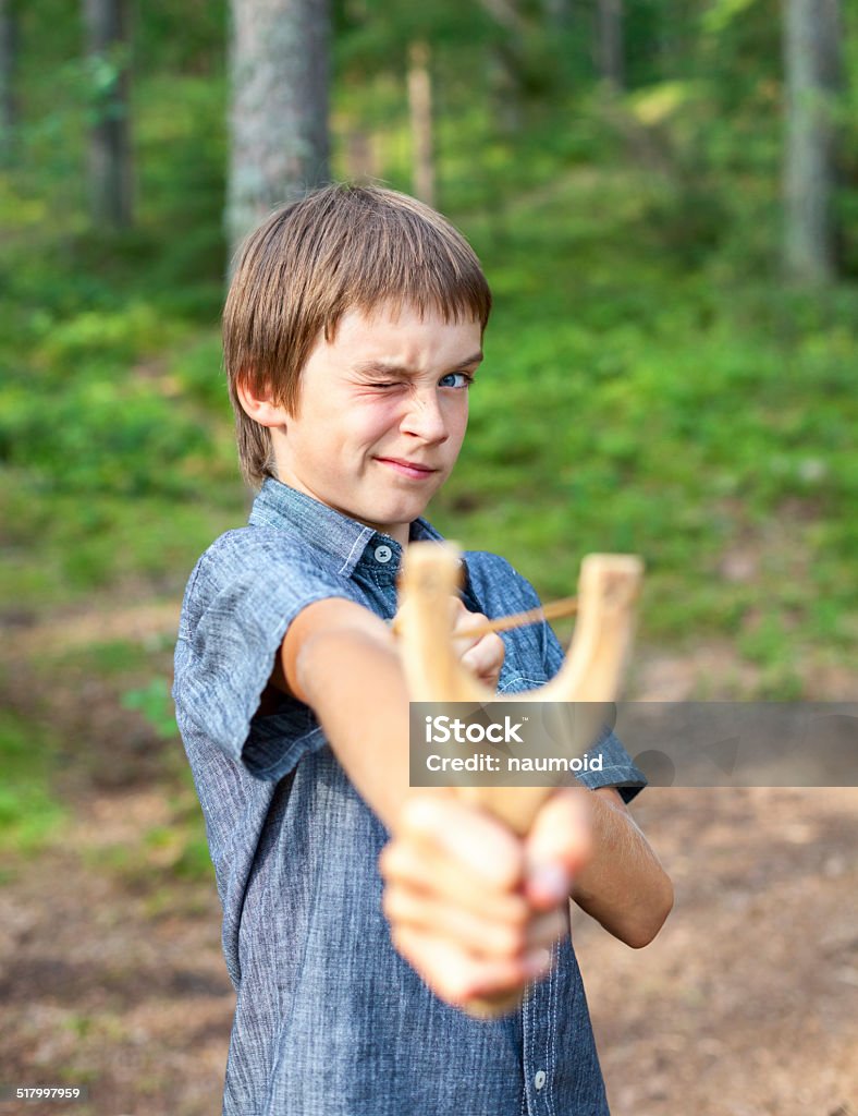 Kid with slingshot Boy aiming wooden slingshot outdoors Accuracy Stock Photo