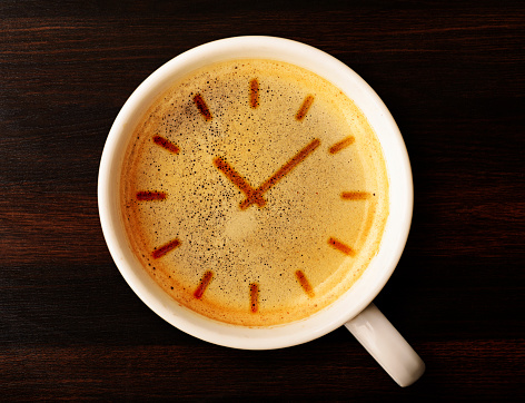 coffee time. cup of fresh espresso with clock sign, view from above