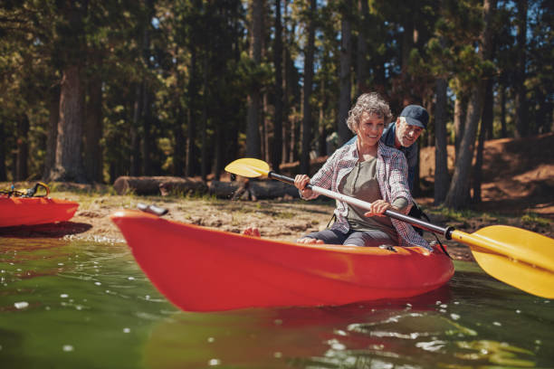 donna matura apprendimento di fila in kayak - canoeing canoe senior adult couple foto e immagini stock