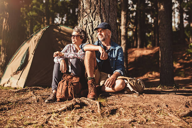 dojrzała para relaksujący w ich pole namiotowe - camping hiking tent couple zdjęcia i obrazy z banku zdjęć