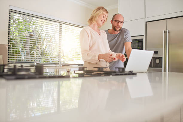 istock Happy couple using laptop in the kitchen at home 518001182
