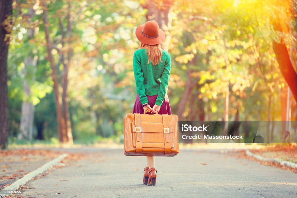 Beautiful redhead girl with suitcase in the park. Adult Stock Photo