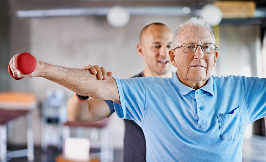 Shot of a physiotherapist helping a senior man with weights