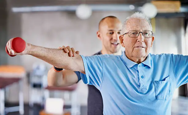 Shot of a physiotherapist helping a senior man with weights