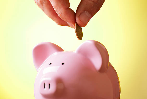 istock Man placing a coin into a piggy bank 518017765