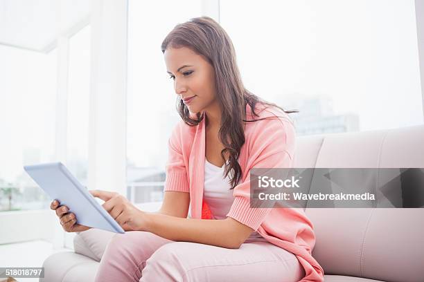 Pretty Brunette Using Her Tablet Pc On The Couch Stock Photo - Download Image Now - 20-29 Years, 25-29 Years, Adult