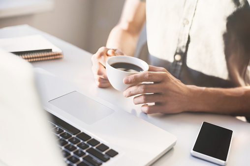 Male hands holding cup of coffee in the office