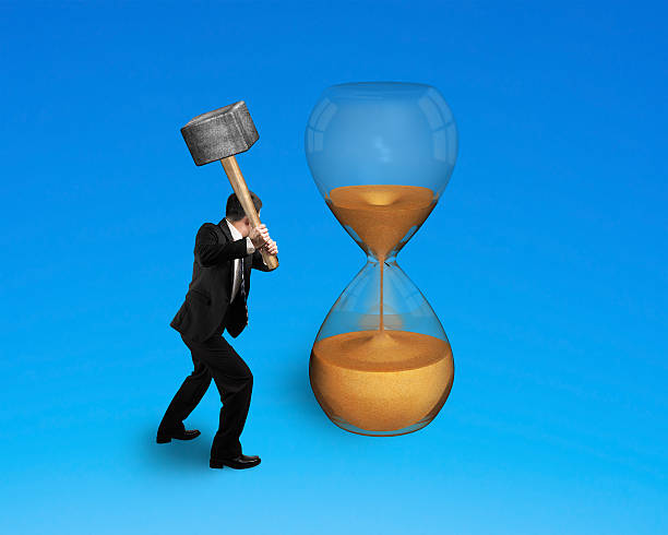istock male hand holding hammer to hit hourglass 518018975