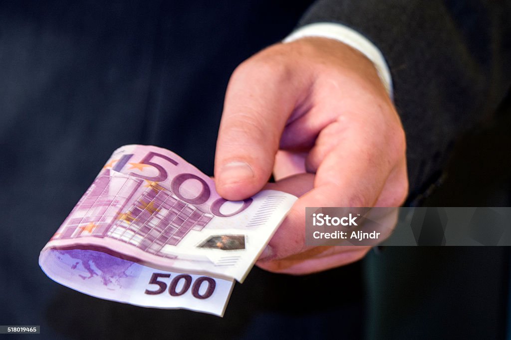 hand giving money Man hand gives 500 euros banknote, the man is dressed in gray suit and white shirt, Five Hundred Euro Banknote Stock Photo