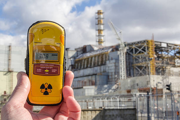 UKRAINE. Chernobyl Exclusion Zone. - 2016.03.19. Dosimeter and Chernobyl Nuclear Power Plant and shelter facility. Front view  radiation dosimeter stock pictures, royalty-free photos & images