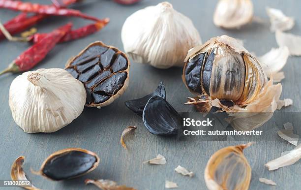 Black Garlic Artistically Scattered On Grey Background Stock Photo - Download Image Now