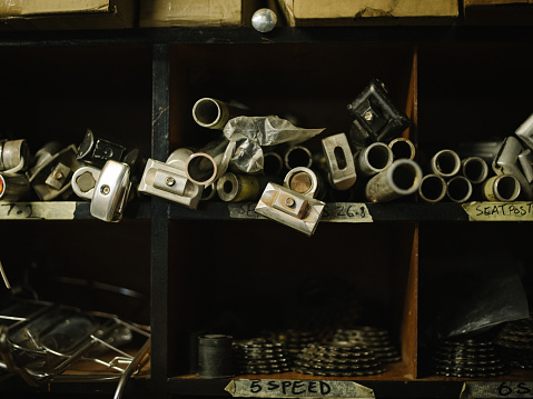 A variety of metal pipes and bicycle components arranged in wooden shelves in a well-used workshop