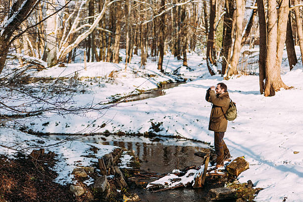 Hiker Looking Through Binoculars In A Sunny Winter Forest