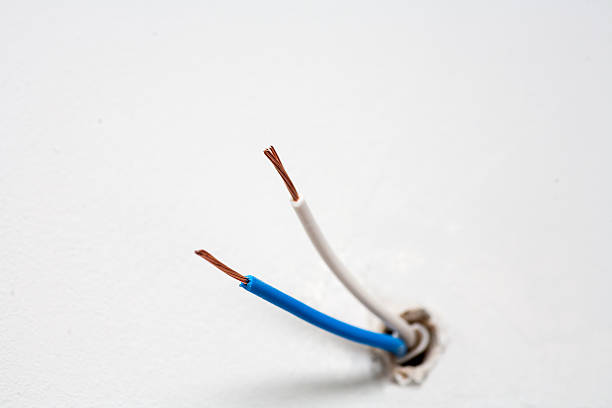 istock Two electric wires in white wall, copyspace 518025902