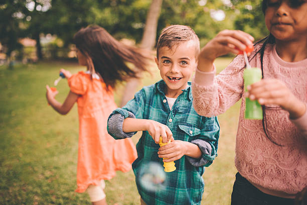мальчик с промежуток улыбка играя с пузырьками и друзьями - toothless smile фотографии стоковые фото и изображения