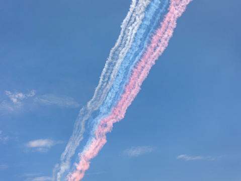 Color smokes in the form of Russian flag (tricolor) made by jet aircrafts against blue sky background.