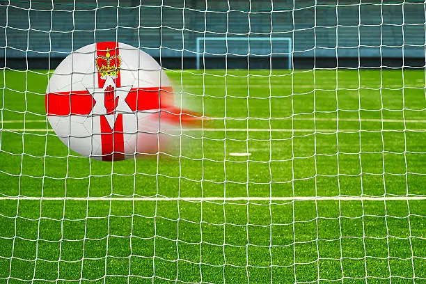 Shot on goal, soccer ball with the flag of North Ireland in the net