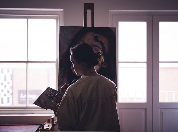 mulher um trabalhar num lona de artista em um estúdio com windows - women artist painting easel imagens e fotografias de stock