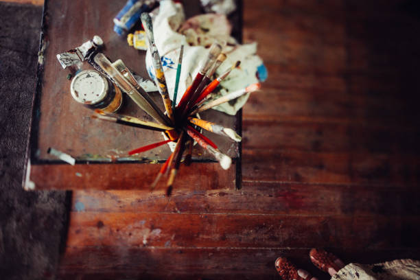Art studio wooden table with paintbrushes paint tubes and rag