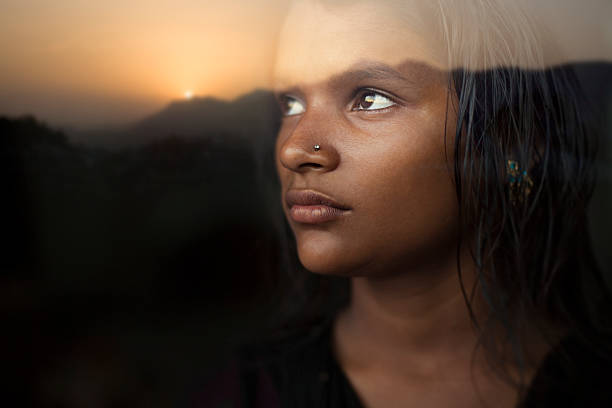 sereine jeune fille regardant le coucher de soleil vue à partir de la fenêtre en verre. - indian girls photos et images de collection