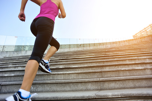 Runner athlete legs running on stairs. woman fitness jogging workout wellness concept.