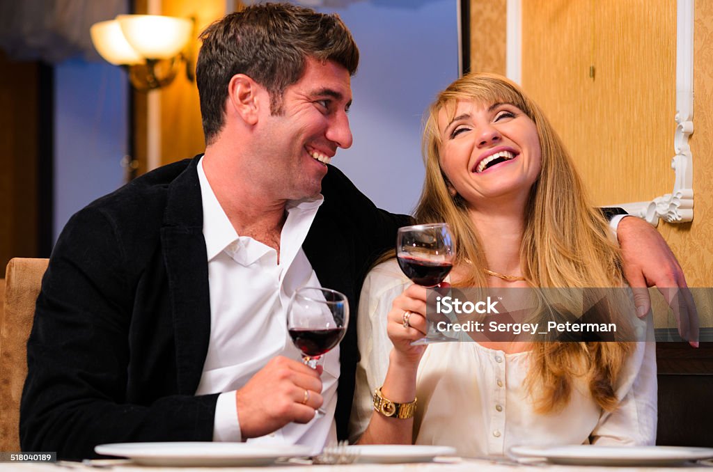 couple is sitting at restaurant laughing embracing couple is sitting at restaurant and drinking wine Adult Stock Photo