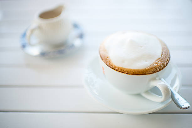 istock Coffee mug with syrup on white wooden table. 518044265