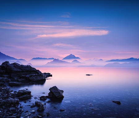 Tranquil landscape at sunset with sea and mountains in the distance.