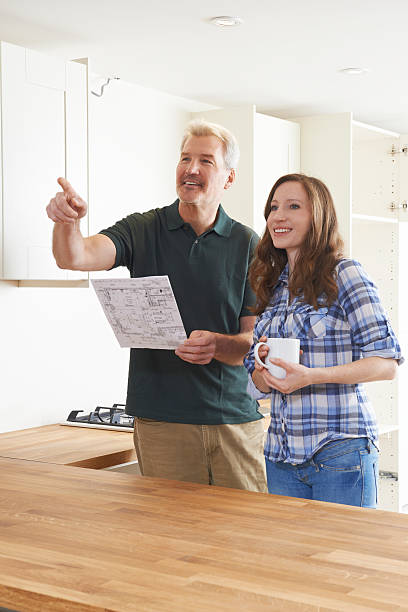 istock Woman With Carpenter Looking At Plans For New Kitchen 518059470