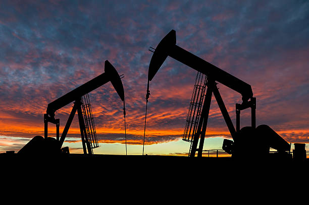 ciel dramatique sur les silhouettes gréer dans rural alberta, canada - oil pumping unit at sunset time photos et images de collection