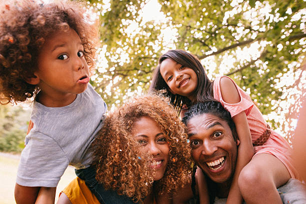 hermosa familia afroamericana riendo y haciendo caras más desenfadado - family grass toddler african descent fotografías e imágenes de stock