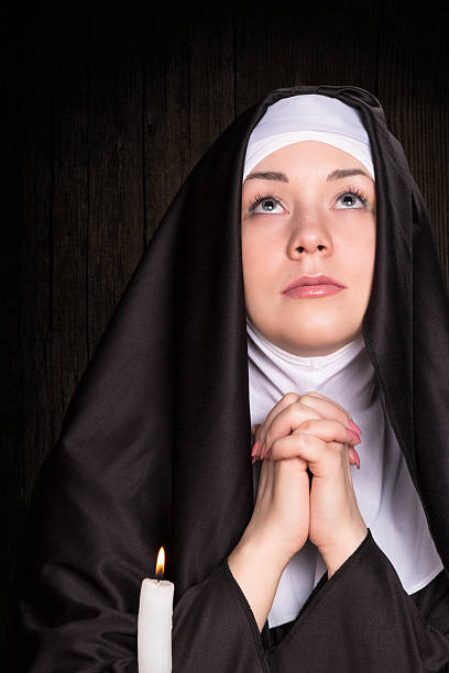 Nun praying and burning candle Portrait of praying nun, who looks up from a burning candle near nun catholicism sister praying stock pictures, royalty-free photos & images
