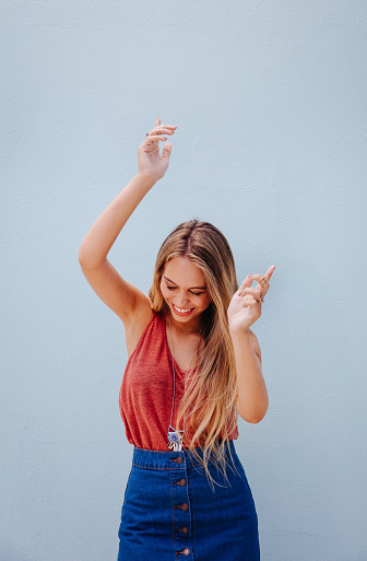 Young beautiful happy stylish hipster girl dancing, isolated on blue wall background