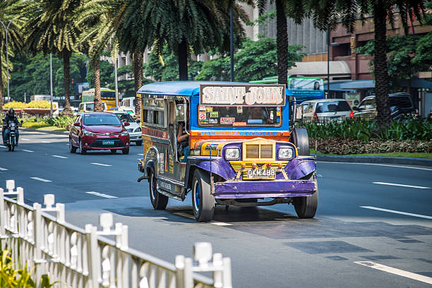Manila, Philippines - April 29, 2014: Colorful Jeepney in Makati City, Manila, Philippines. We can see some passengers on board. Jeepneys are the most popular means of public transportation in the Philippines. They are known for their crowded seating and kitsch decorations, which have become a ubiquitous symbol of Philippine culture and art.