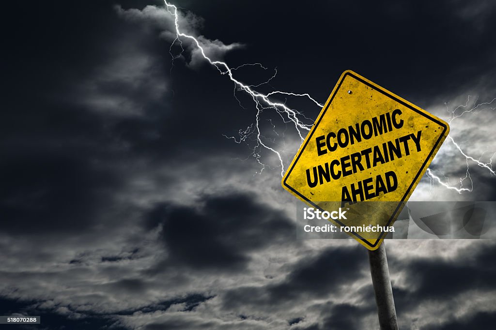 Economic Uncertainty Ahead Sign With Stormy Background Economic Uncertainty sign against a stormy background with lightning and copy space. Dirty and angled sign adds to the drama. Recession Stock Photo