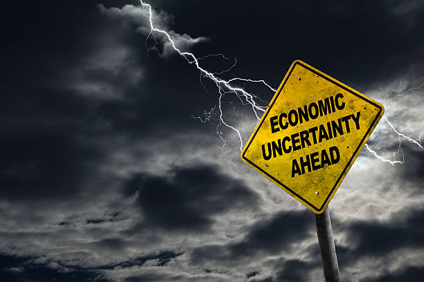 Economic Uncertainty Ahead Sign With Stormy Background Economic Uncertainty sign against a stormy background with lightning and copy space. Dirty and angled sign adds to the drama. uncertainty stock pictures, royalty-free photos & images