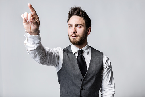 Portrait of young businessman pressing a button on an imaginary screen.