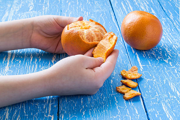 Children's hands peeling tangerine