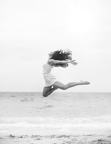 Beautiful girl jumping at the beach