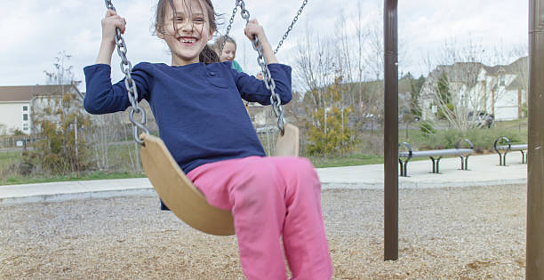 istock Young girls swinging on a swing set at a park 518092110