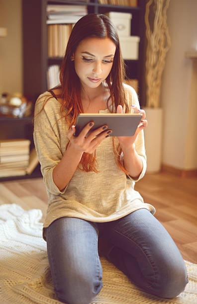 istock young brunette woman in home interior Using Digital Tablet 518093014