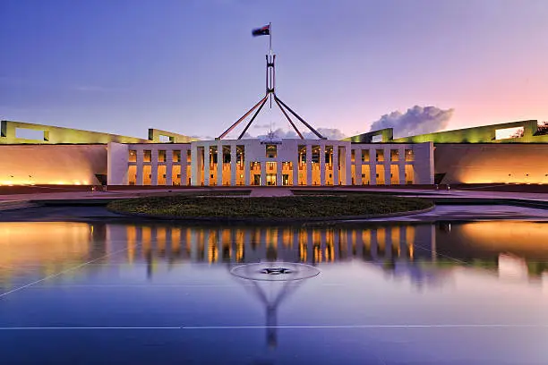 colourful reflection of Canberra's new parliament building in a fontain pond at sunset.