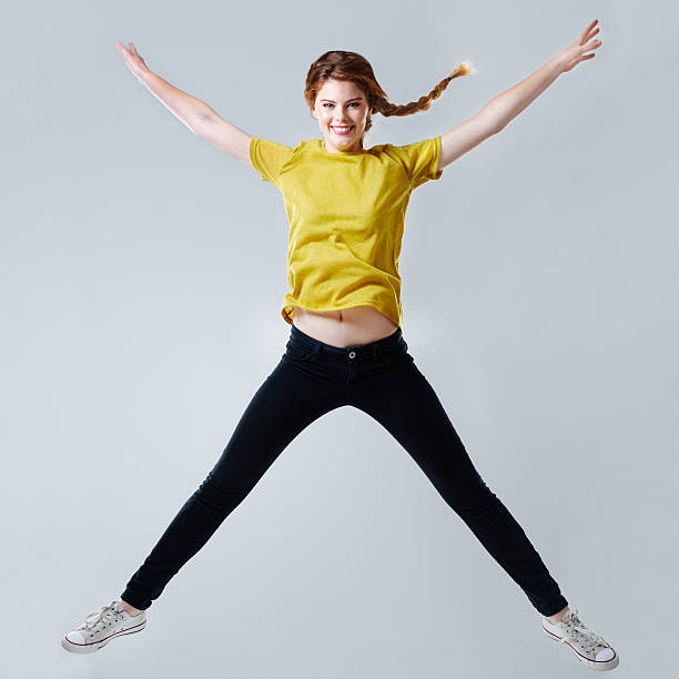 Star jumps! Full-length studio shot of a beautiful young woman doing a star jump legs apart stock pictures, royalty-free photos & images