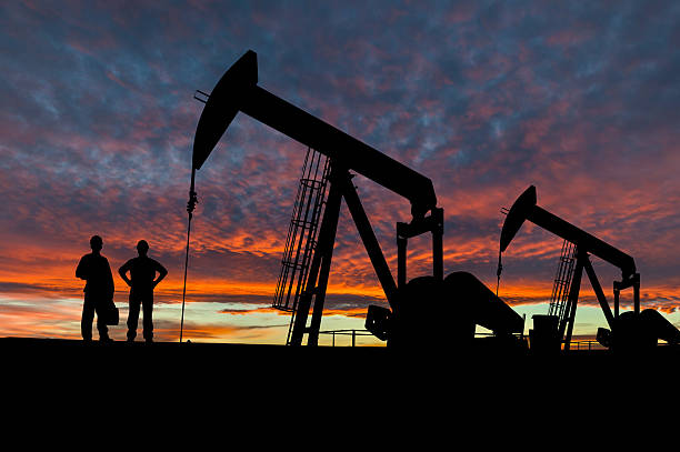 silhouettes de travailleurs pumpjacks et aux huiles - engineer oil rig oil field manual worker photos et images de collection