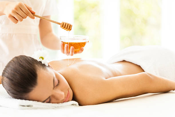 istock Masseuse pouring honey on woman's back 518095495
