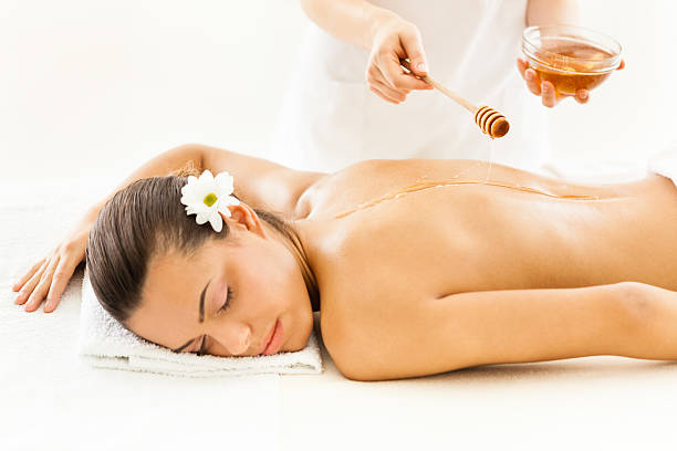 istock Masseuse pouring honey on woman's back 518095501